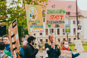 Menschen demonstrieren mit Schildern für Inklusion und Teilhabe in der Rostocker Innenstadt